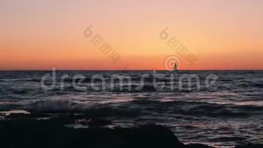 令人难以置信的橙色日落，小帆船在地平线上。 日落时漂浮在海上的小帆船剪影。 赛的剪影